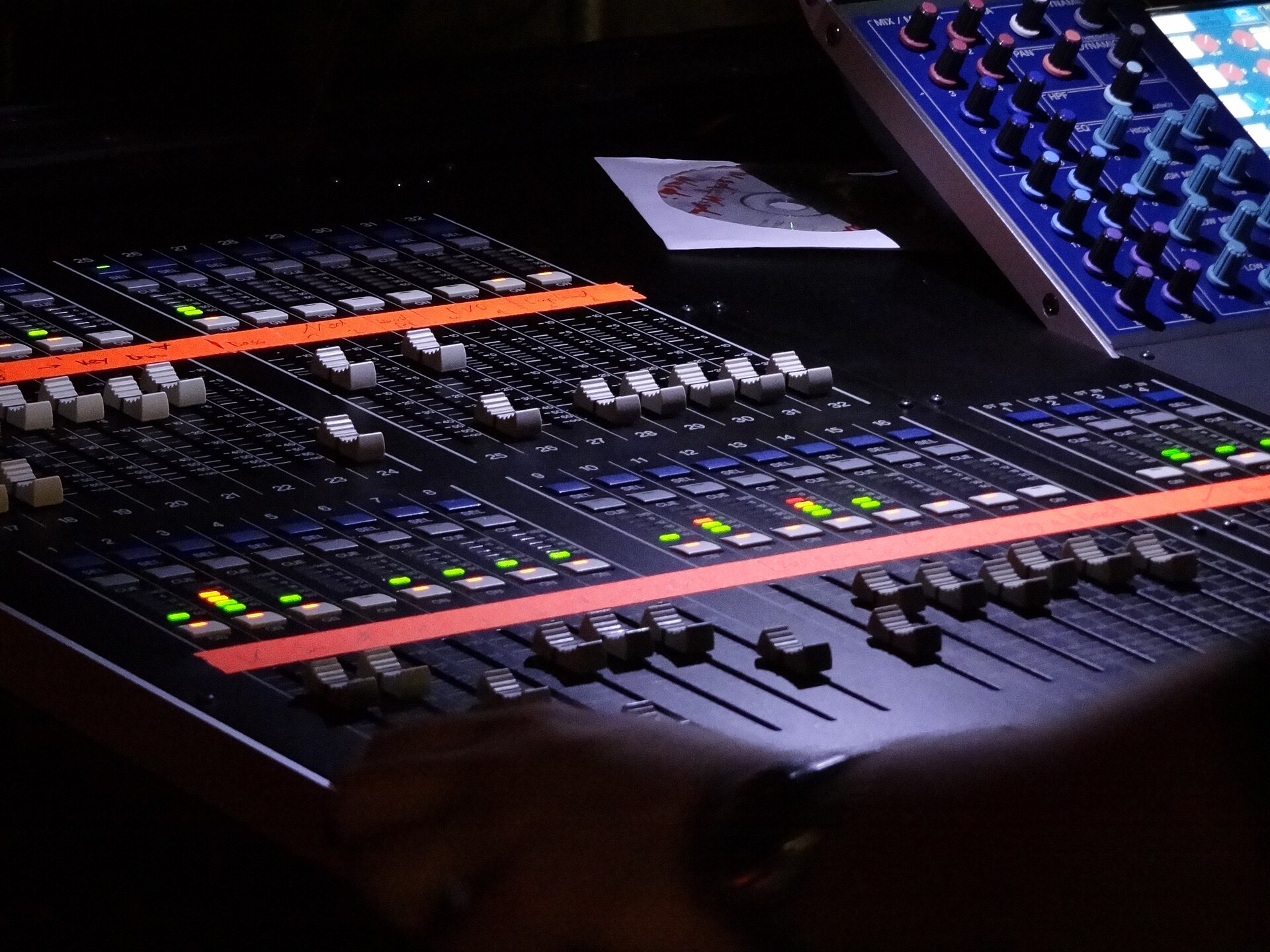 A digital live-sound mixing console with faders, meters and hand-written channel tape