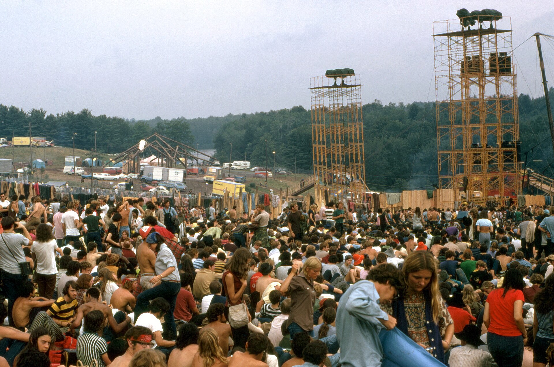 Festival crowds on a hillside facing a stage and tall loudspeaker towers, 1969