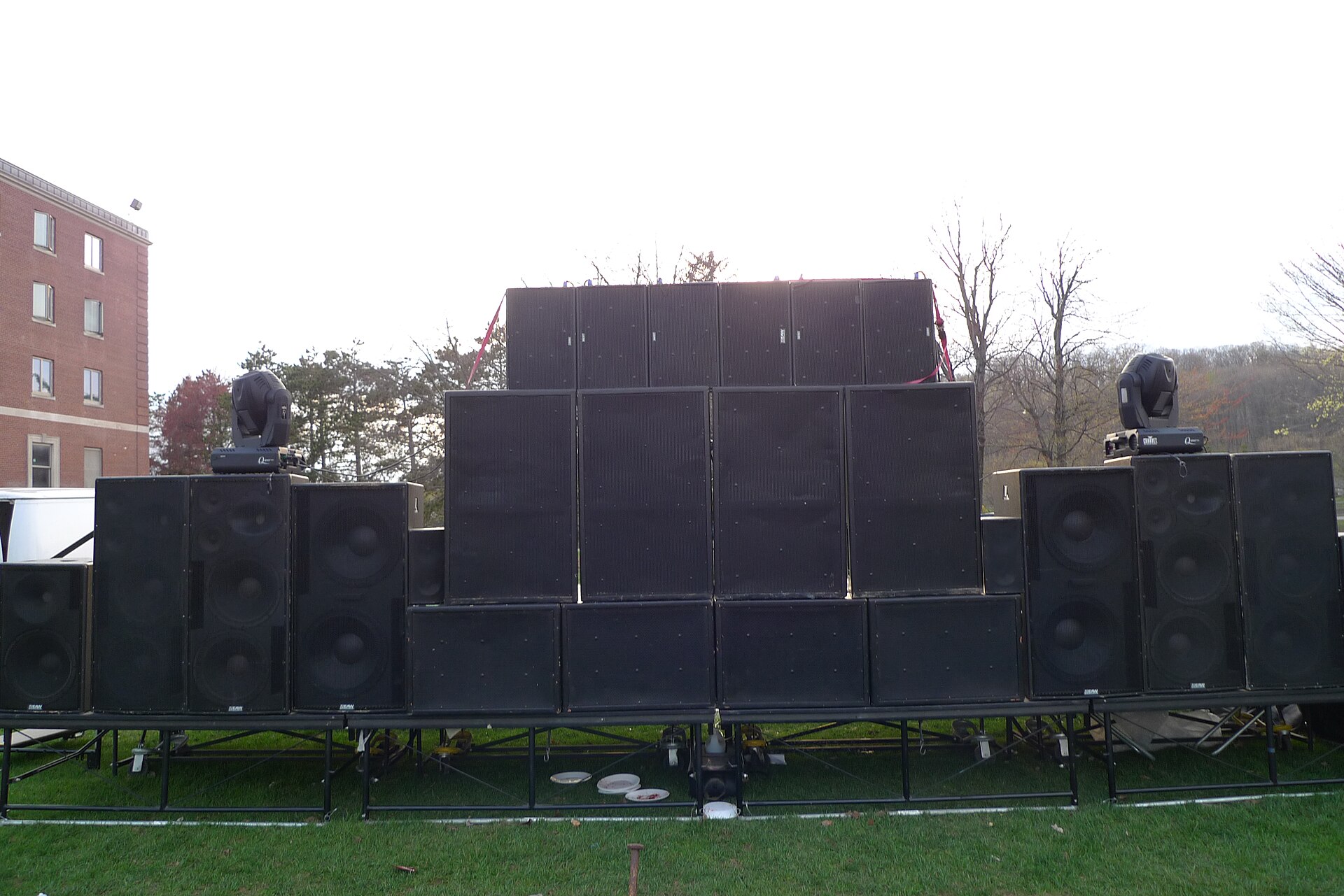 A large loudspeaker and subwoofer wall built on a riser on a lawn